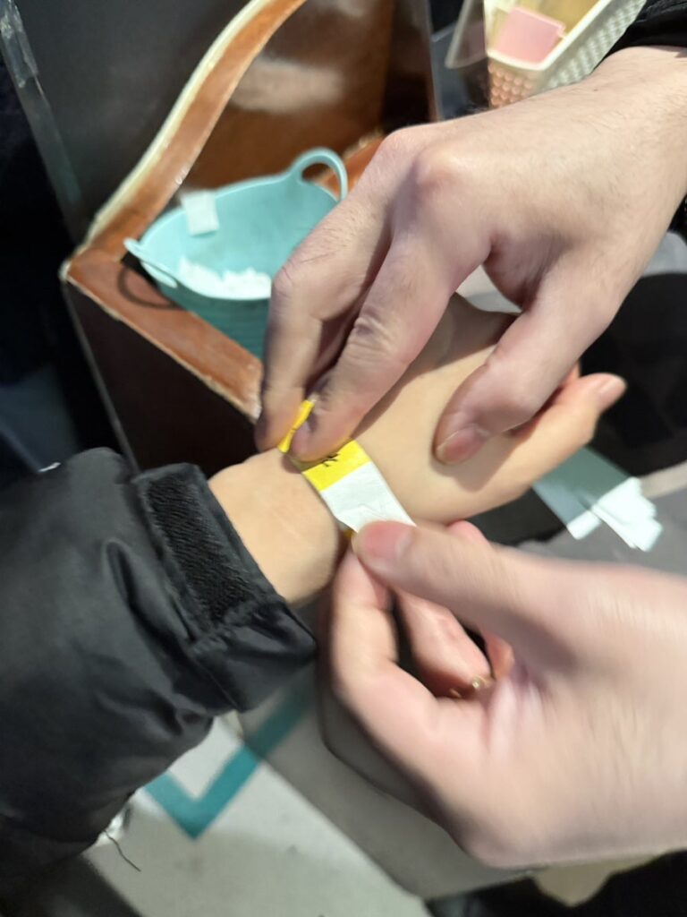 Staff fastening a paper wristband at the entrance