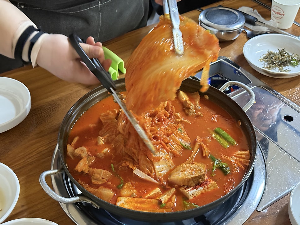 Lifting a long whole leaf of aged kimchi