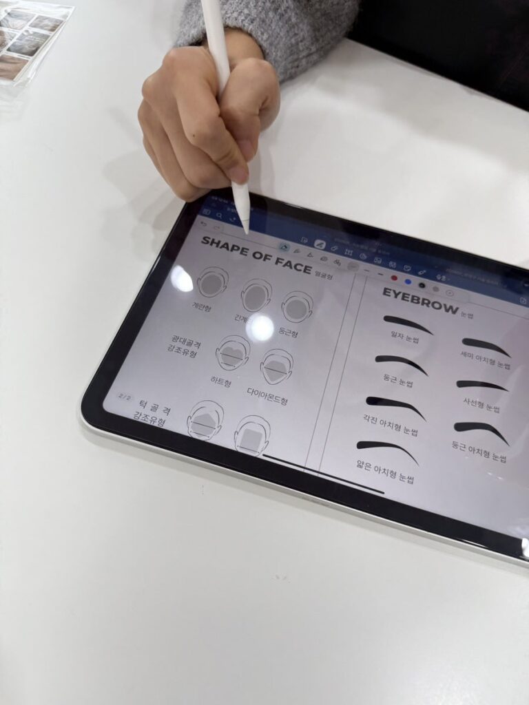 Owner sketching brow shapes on the tablet chart