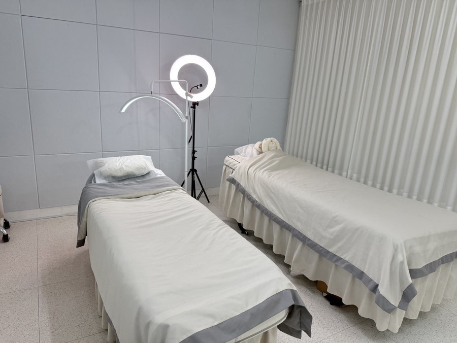 Two treatment beds with a ring light in a bright white room