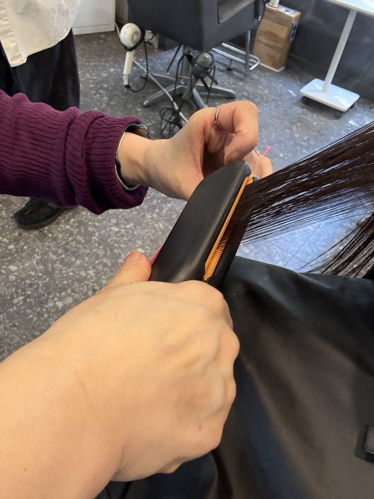 Smoothing the hair strand by strand with a heated tool