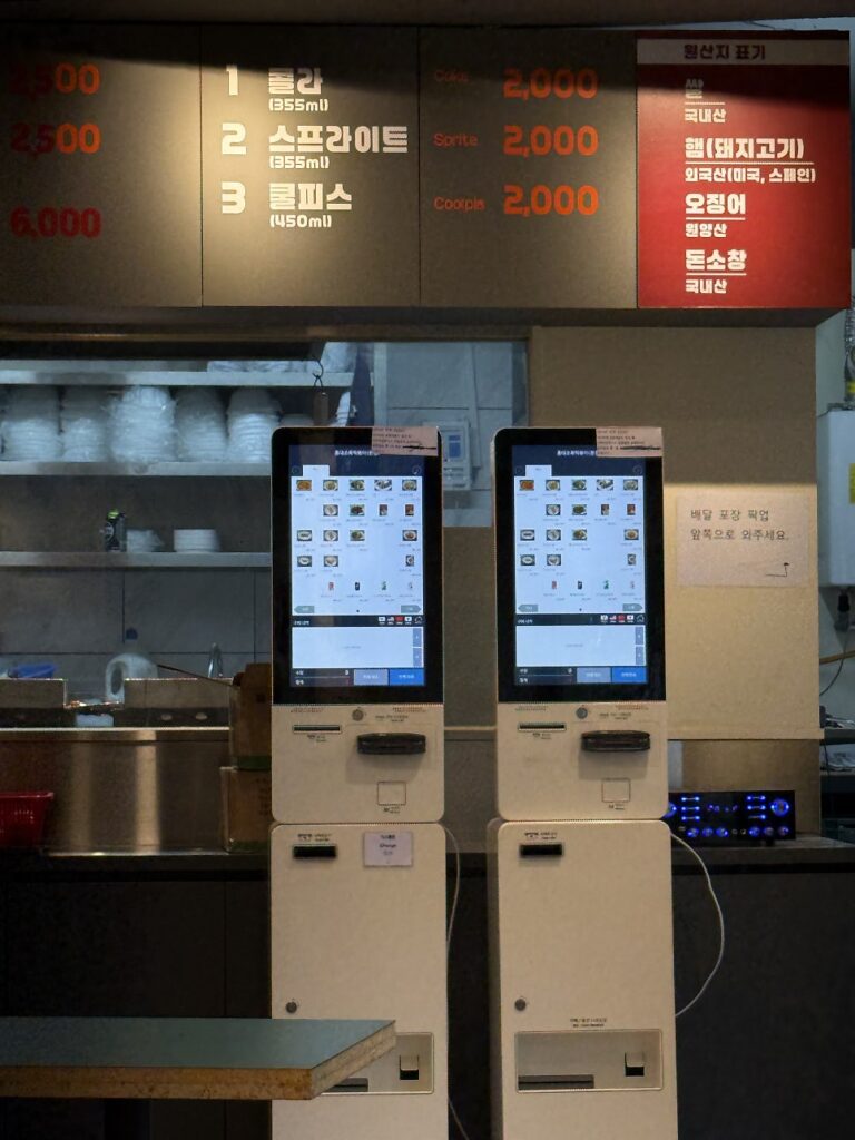 Two ordering kiosks in front of the open kitchen