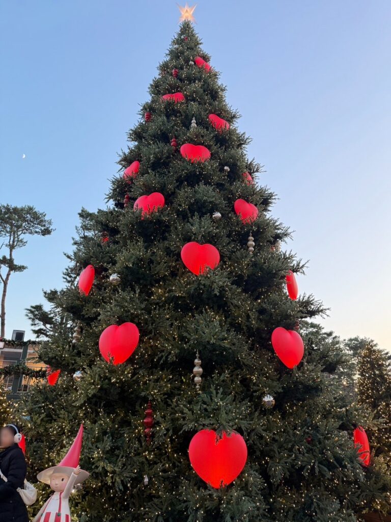 Giant Christmas tree decorated with red hearts against a clear sky