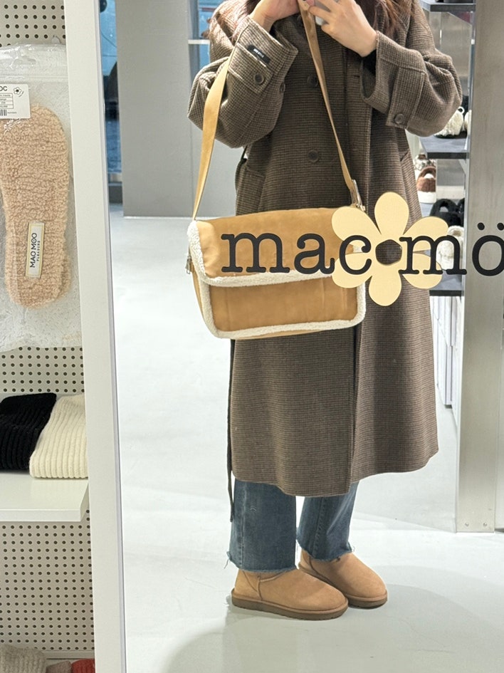 The camel crossbody bag worn with a long coat and fleece boots