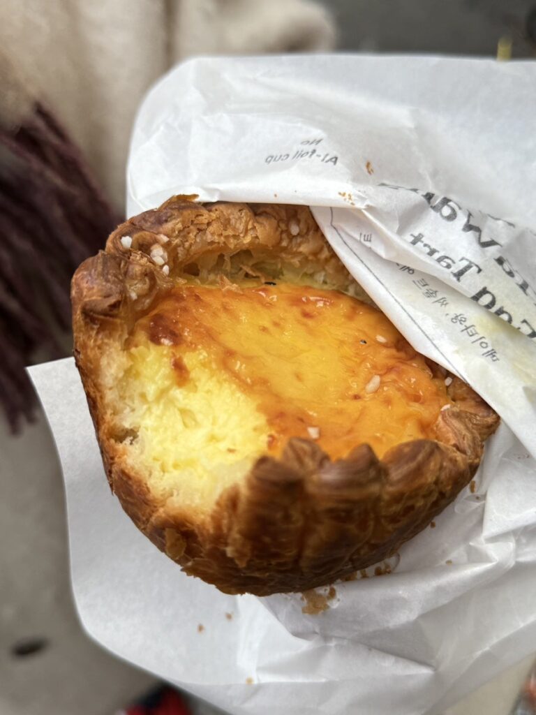 Giant egg tart held in a paper wrapper