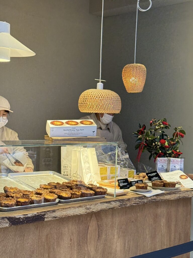 Counter with trays of egg tarts under pendant lamps