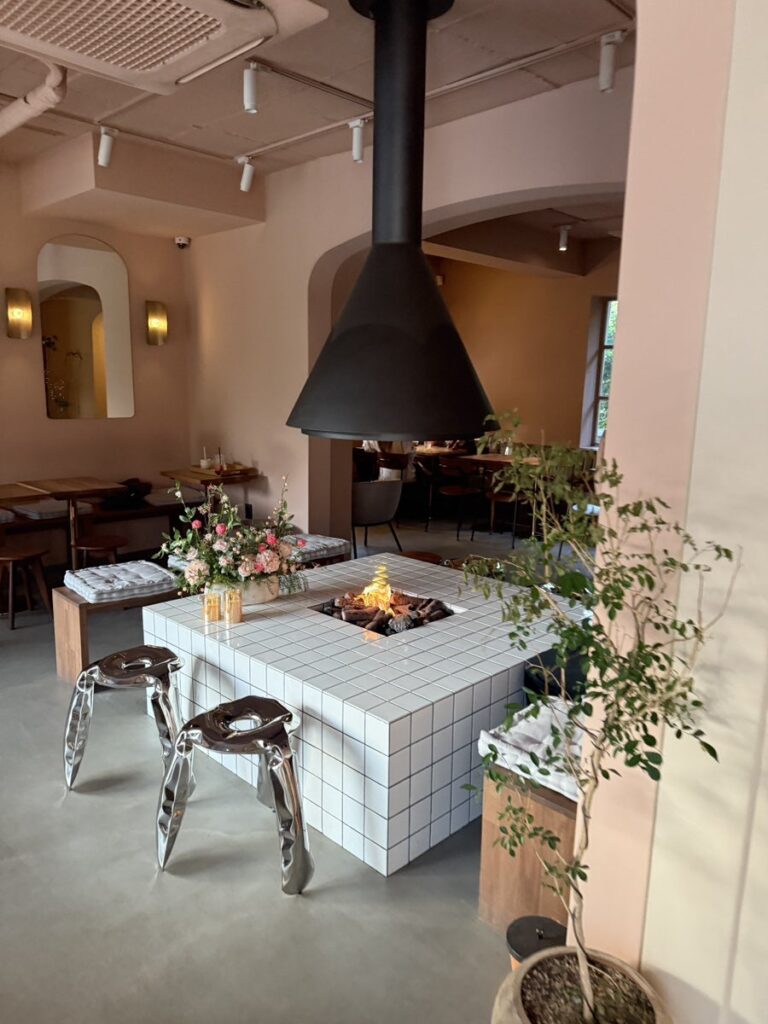 Indoor white-tiled fire pit with a black hood and flowers