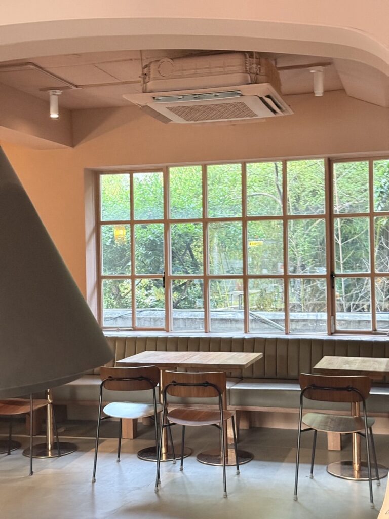 Wooden tables by large grid windows looking out at trees