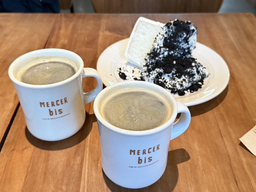 Two Americanos in Mercer bis mugs next to the cake