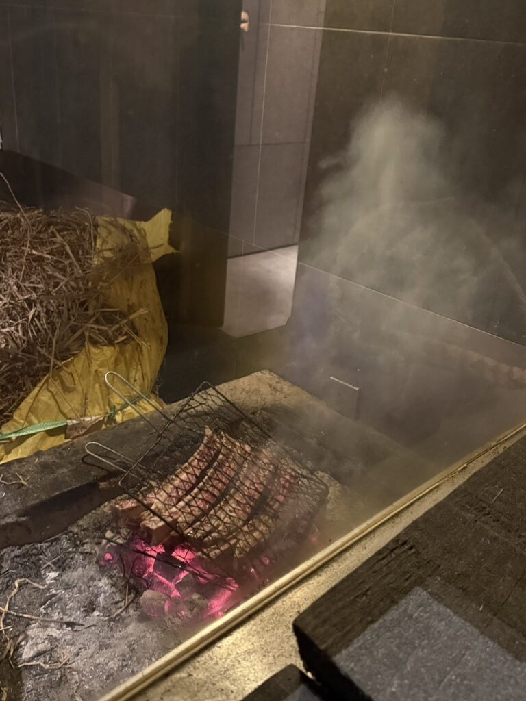 Beef ribs being smoked over a straw fire