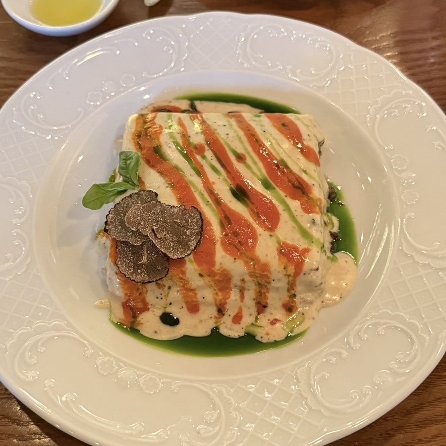 Truffle lasagna topped with sliced black truffle and green herb oil