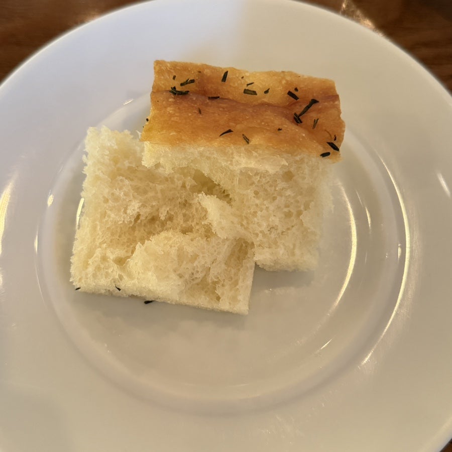 Complimentary focaccia-style bread on a white plate
