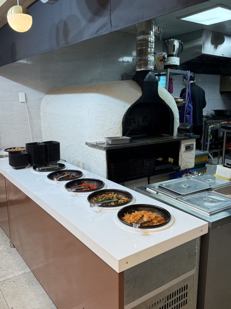 Self-serve side dish bar in front of the stone oven