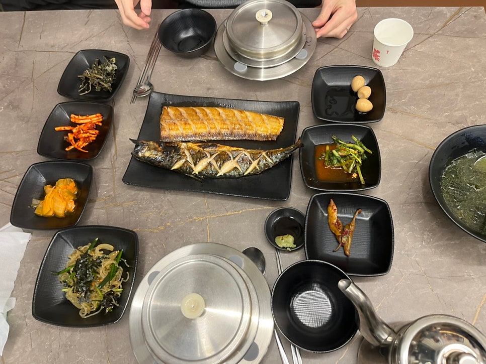Full table with grilled fish, pot rice and side dishes