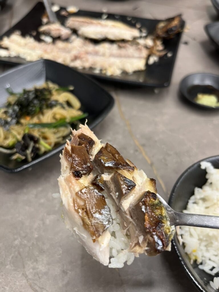 Piece of crispy grilled mackerel lifted over rice