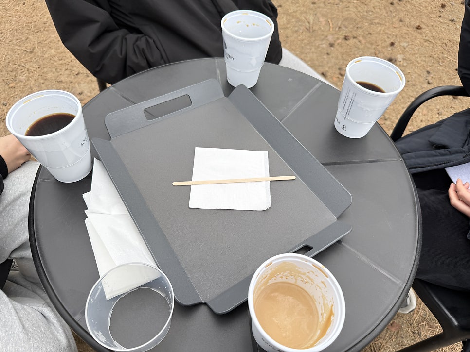 Coffee in logo cups on a tray outdoors
