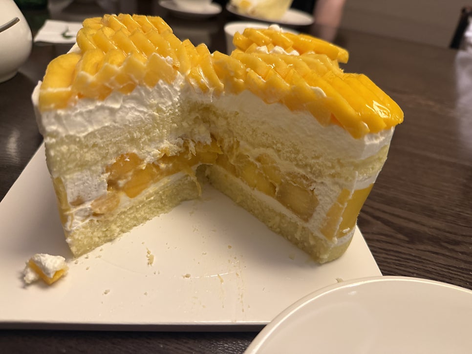 Cut mango cake showing layers of cream and mango