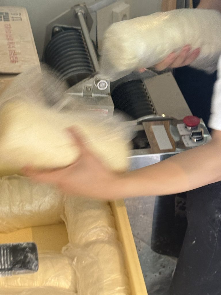 Fresh udon noodles coming out of the noodle machine