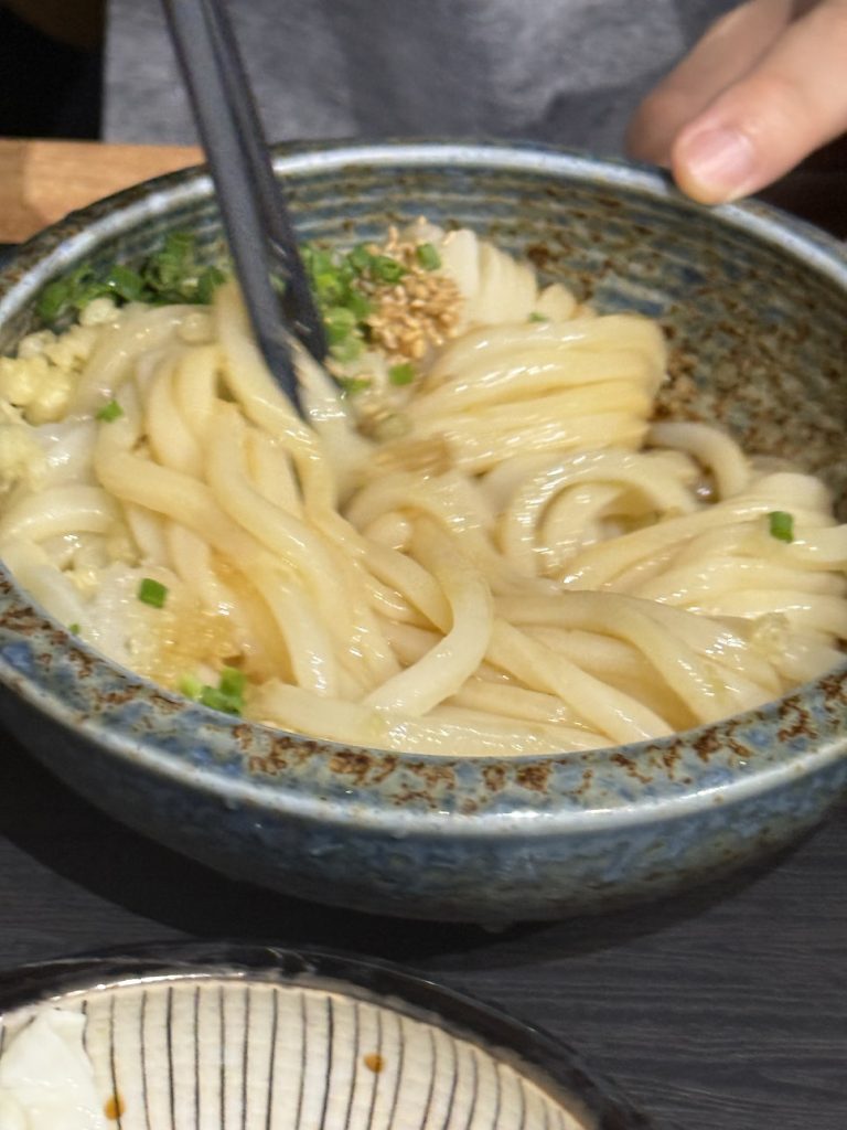 Mixing cold bukkake udon with tsuyu sauce