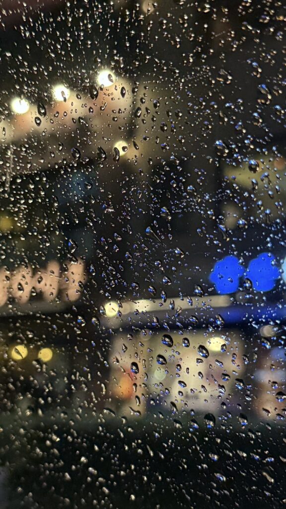 City lights blurred through raindrops on a window at night